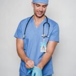 Male doctor in uniform putting on sterile gloves